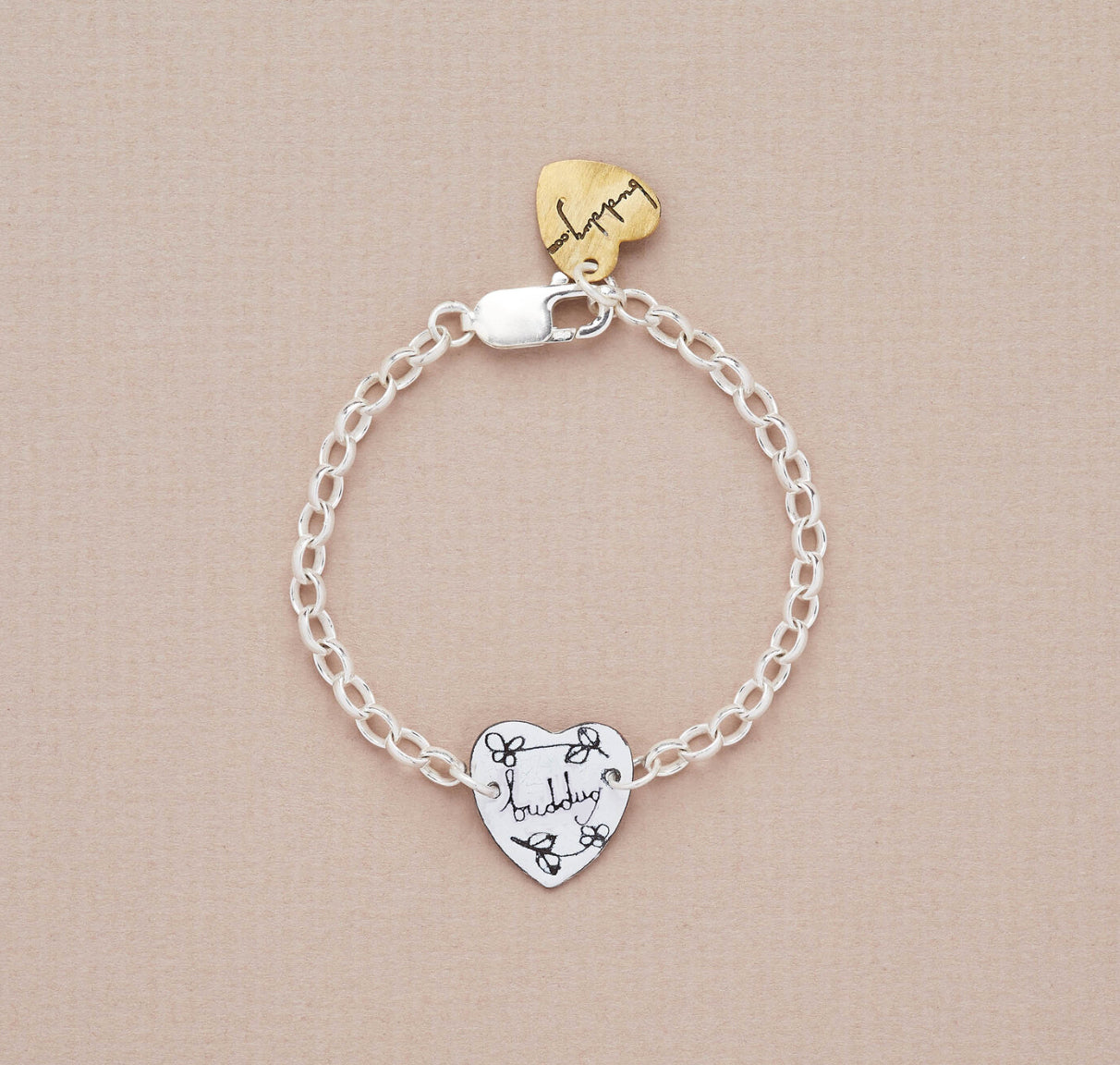 A silver bracelet with a small heart-shaped charm featuring the word 'Buddug' on it, displayed against a neutral background.
