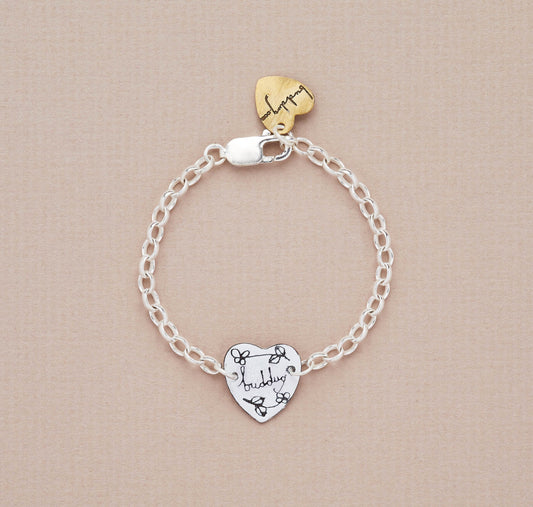A silver bracelet with a small heart-shaped charm featuring the word 'Buddug' on it, displayed against a neutral background.